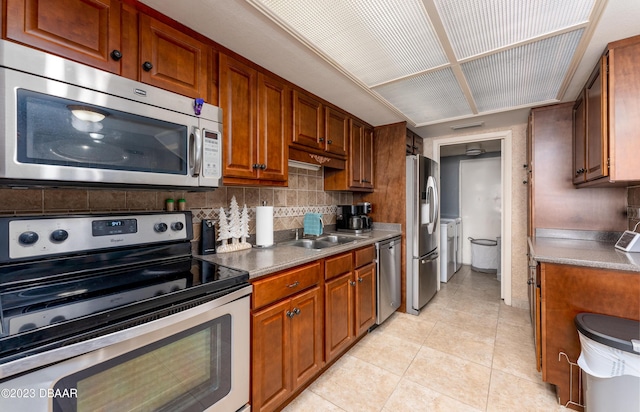 kitchen featuring appliances with stainless steel finishes, sink, light tile patterned floors, and decorative backsplash