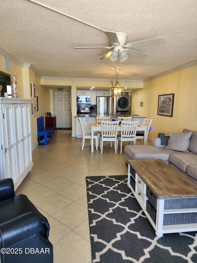 tiled living room with stacked washer / dryer, crown molding, and a textured ceiling