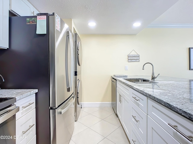 kitchen featuring sink, light tile patterned floors, stainless steel appliances, light stone countertops, and white cabinets