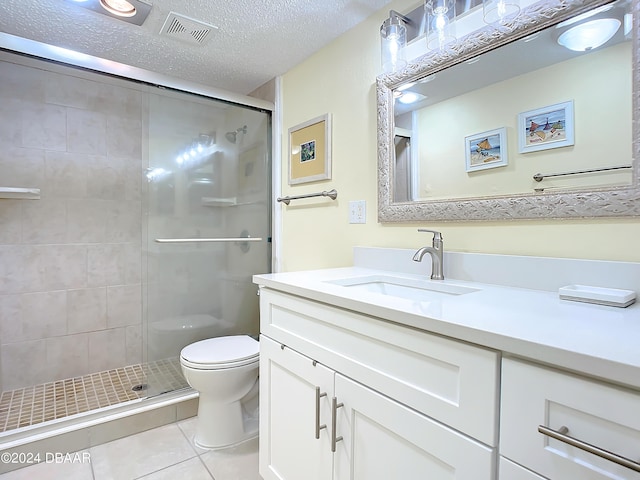 bathroom featuring tile patterned flooring, vanity, a textured ceiling, toilet, and walk in shower