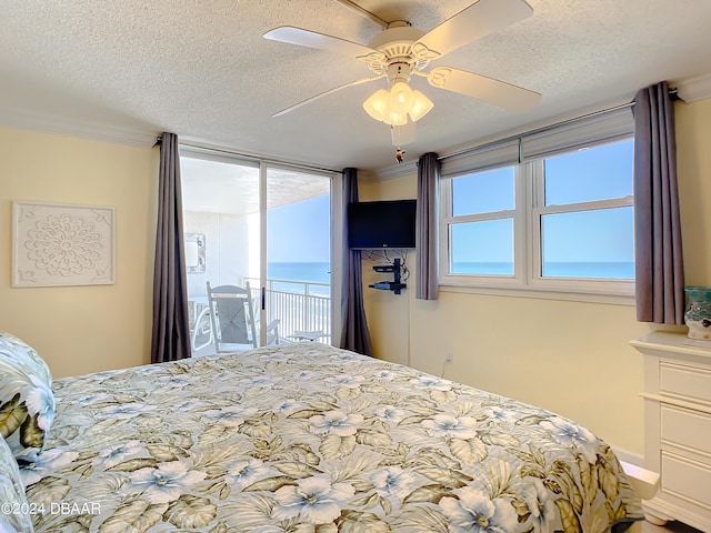 bedroom with ceiling fan, access to exterior, and a textured ceiling