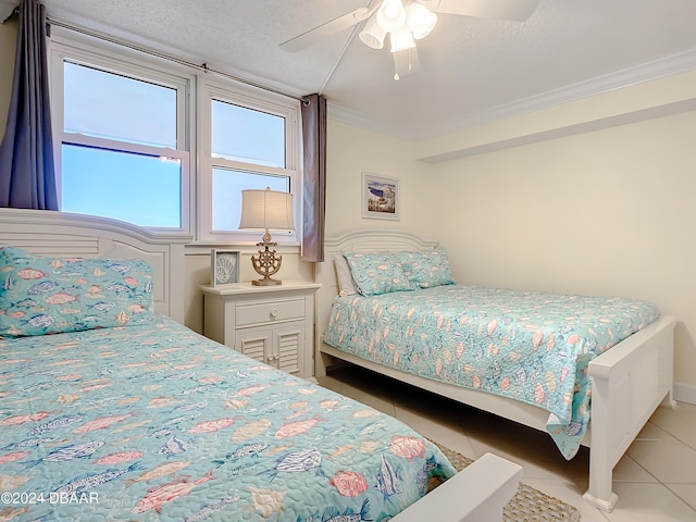 tiled bedroom featuring a textured ceiling, ornamental molding, and ceiling fan