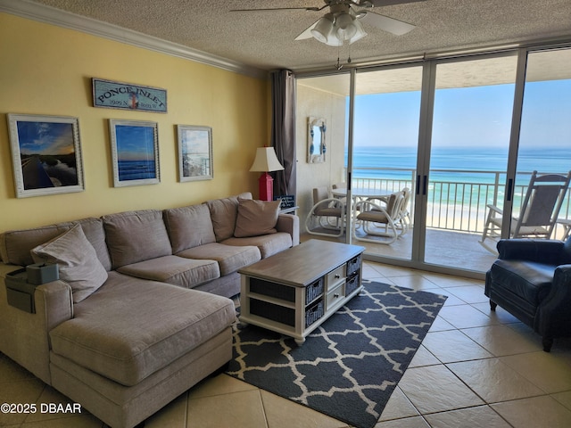 living room featuring crown molding, a water view, expansive windows, a beach view, and a textured ceiling