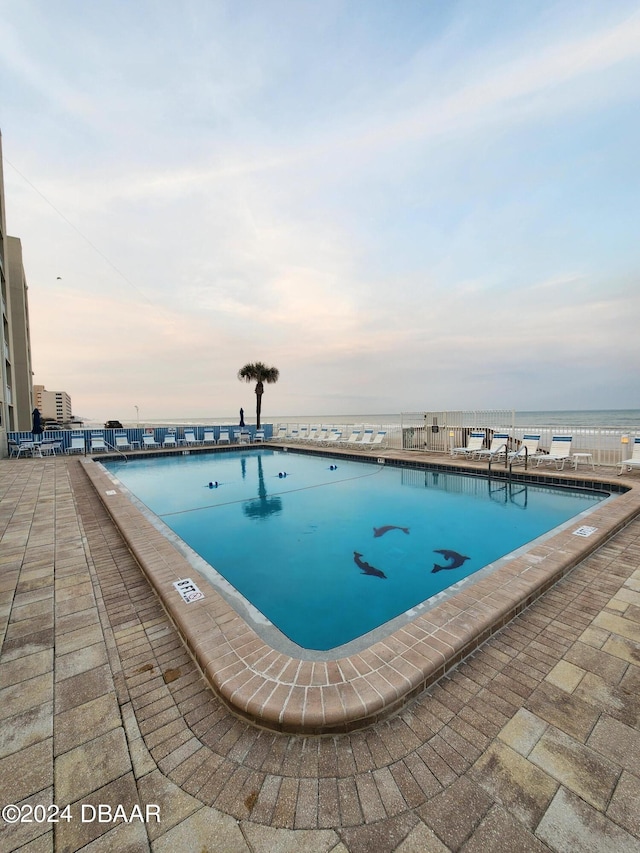 pool at dusk featuring a water view