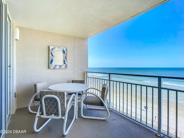 balcony with a water view and a view of the beach