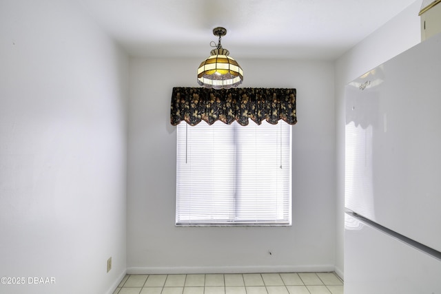 unfurnished dining area with light tile patterned flooring and baseboards