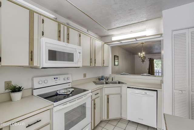 kitchen with white appliances, a sink, light countertops, and a chandelier