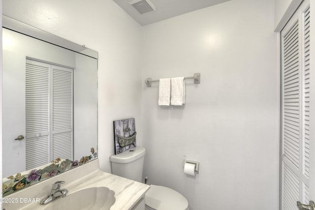 bathroom featuring a closet, toilet, and vanity