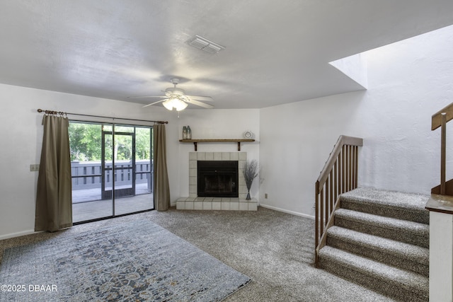 unfurnished living room with carpet floors, stairway, a ceiling fan, baseboards, and a tile fireplace