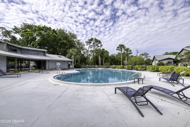 community pool with a patio and fence