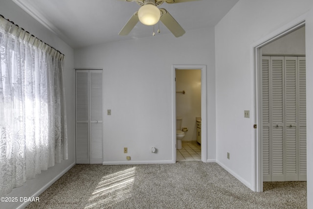 unfurnished bedroom featuring carpet flooring, baseboards, ensuite bathroom, and a ceiling fan