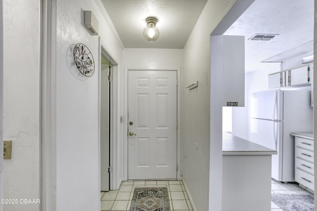 doorway featuring light tile patterned floors and baseboards
