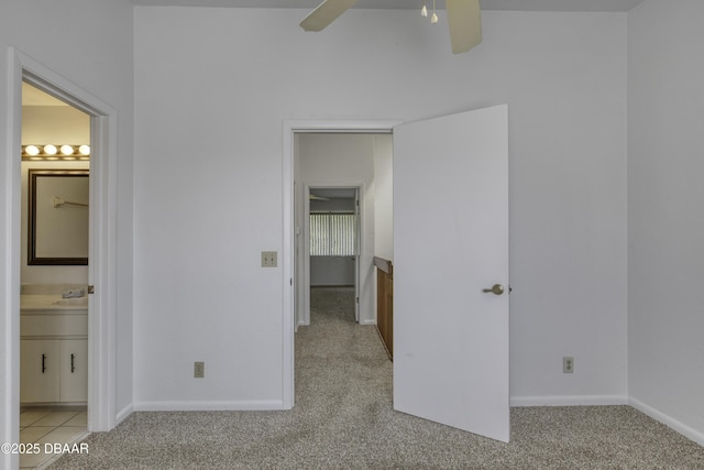 unfurnished bedroom featuring carpet floors, a spacious closet, connected bathroom, and a ceiling fan