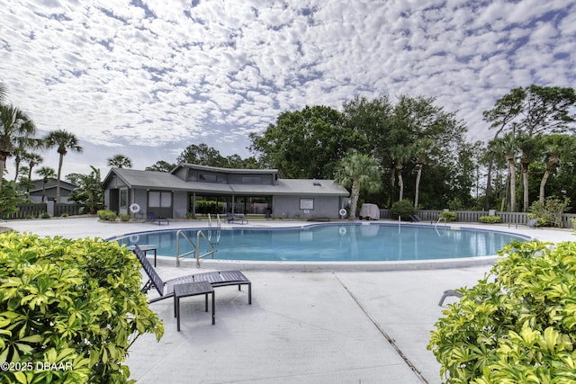 community pool with fence and a patio area