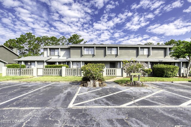 view of building exterior featuring uncovered parking and a fenced front yard