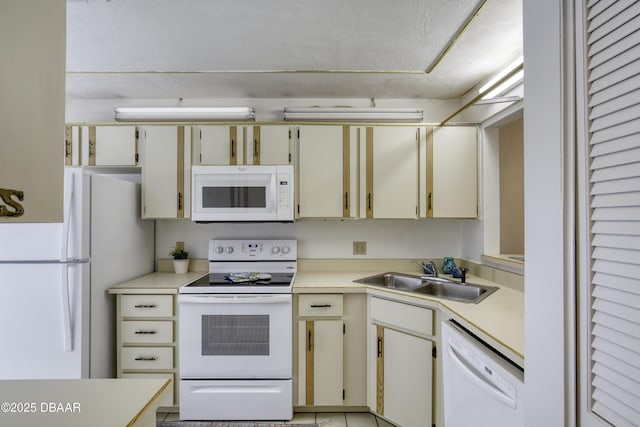 kitchen featuring white appliances, a sink, light countertops, and cream cabinets