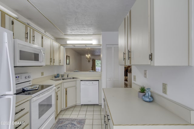 kitchen with white appliances, a sink, light countertops, a chandelier, and light tile patterned floors