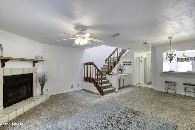 unfurnished living room with carpet flooring, ceiling fan, a chandelier, and a tile fireplace