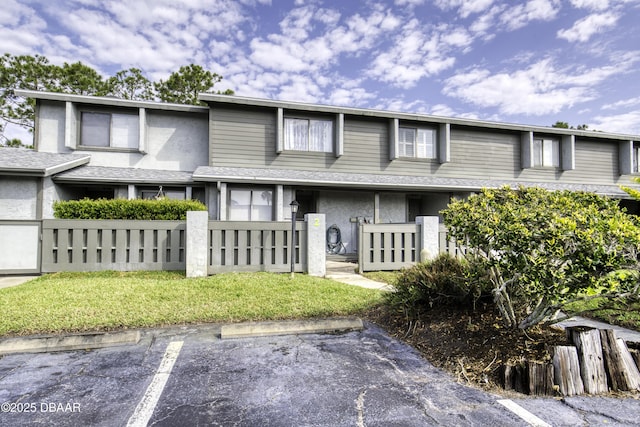 view of front of house with uncovered parking, a fenced front yard, a gate, and stucco siding