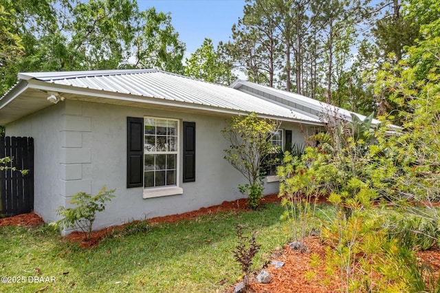 16 Powder Hill Ln, Palm Coast, FL 32164 - view of side of property featuring stucco siding, fence, a lawn, and metal roof