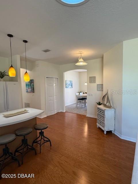 kitchen with dark hardwood / wood-style flooring, white fridge, hanging light fixtures, and a breakfast bar area