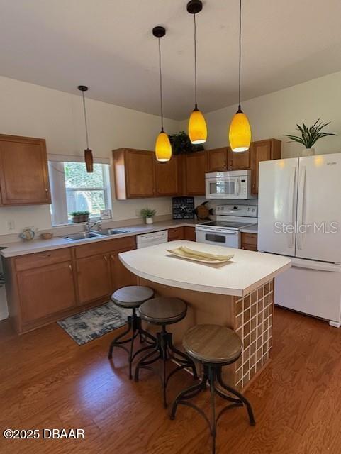 kitchen with white appliances, decorative light fixtures, dark wood-type flooring, and sink