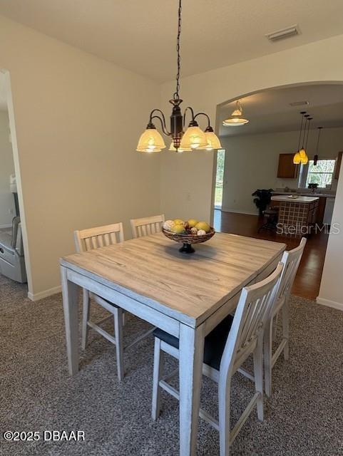 carpeted dining area featuring plenty of natural light and a notable chandelier