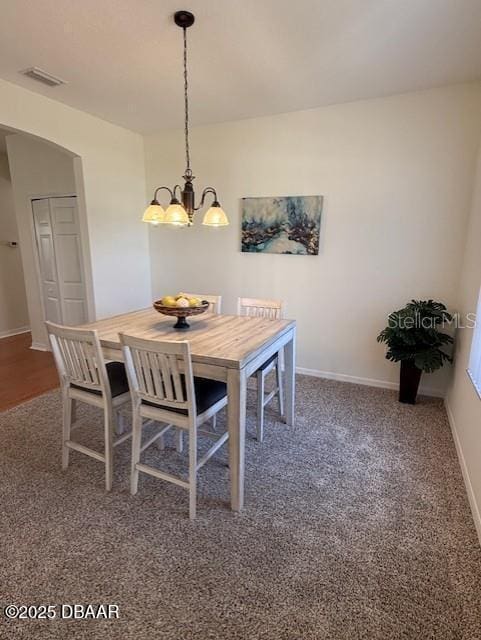 carpeted dining room with an inviting chandelier