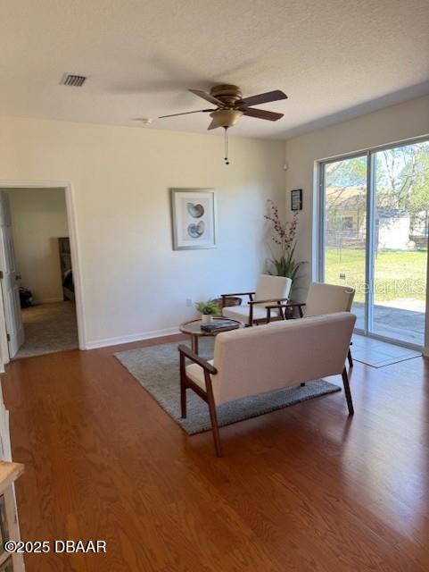 living room featuring hardwood / wood-style floors, a textured ceiling, and ceiling fan