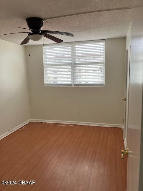 unfurnished room with ceiling fan, wood-type flooring, a textured ceiling, and a wealth of natural light