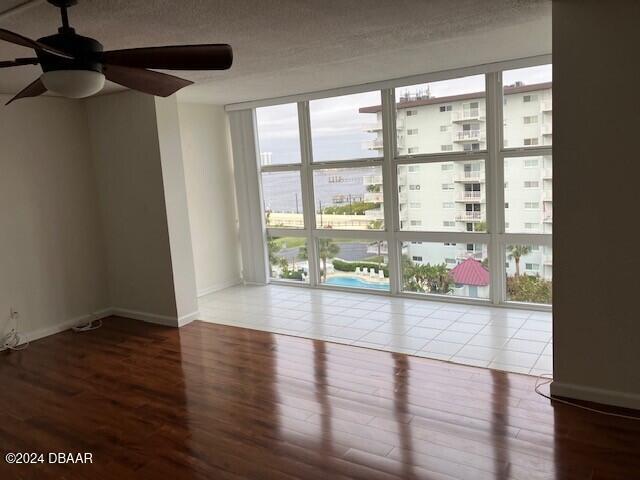 empty room with a textured ceiling, hardwood / wood-style flooring, and ceiling fan