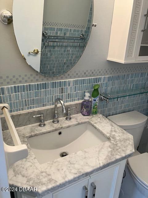 bathroom featuring vanity, toilet, and tile walls