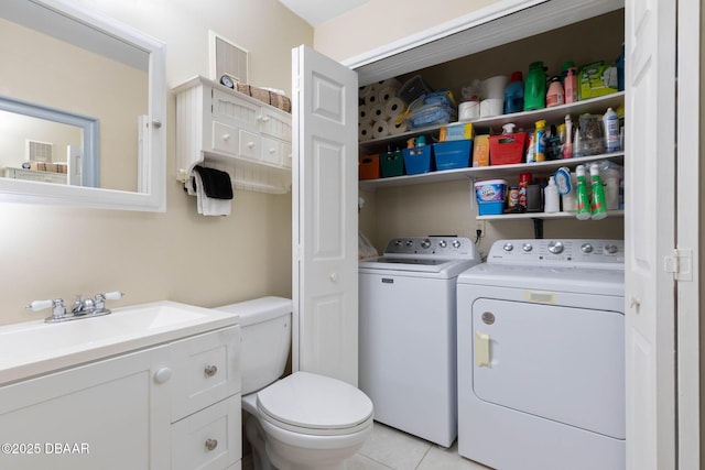 washroom with light tile patterned floors, washing machine and dryer, and sink