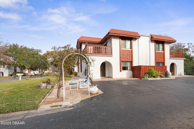 mediterranean / spanish-style home with a balcony, a front yard, and a patio area