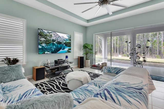 living area with ceiling fan, a wealth of natural light, and baseboards