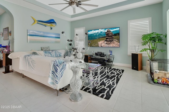 living room with arched walkways, tile patterned flooring, ceiling fan, and baseboards