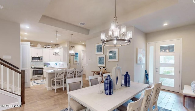 dining area with light wood-type flooring, a notable chandelier, and sink