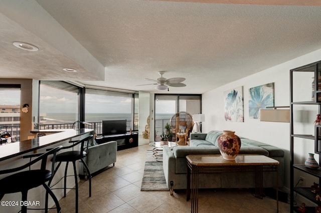 living room with light tile patterned floors, a textured ceiling, floor to ceiling windows, and ceiling fan