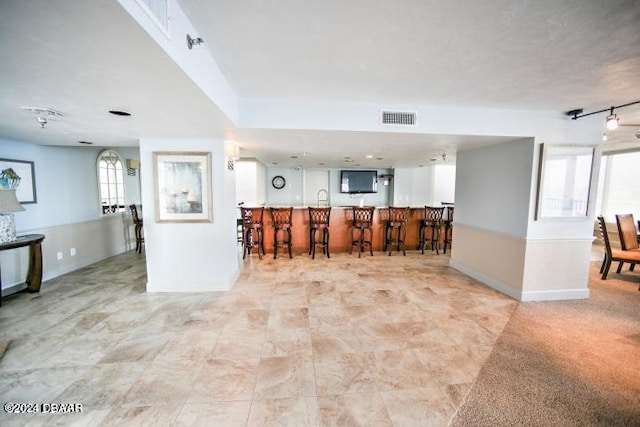 kitchen with a kitchen breakfast bar and light carpet