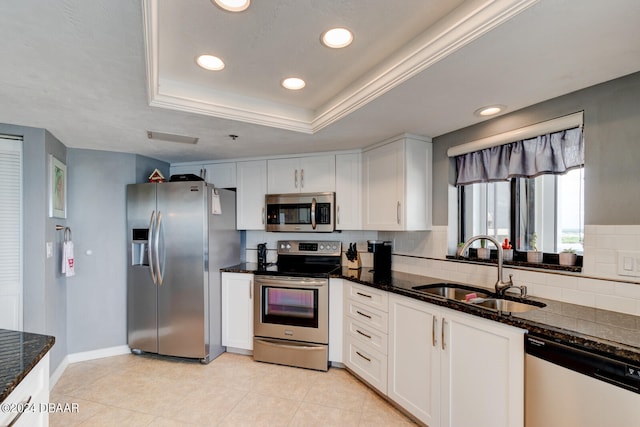 kitchen featuring dark stone counters, white cabinets, sink, backsplash, and appliances with stainless steel finishes