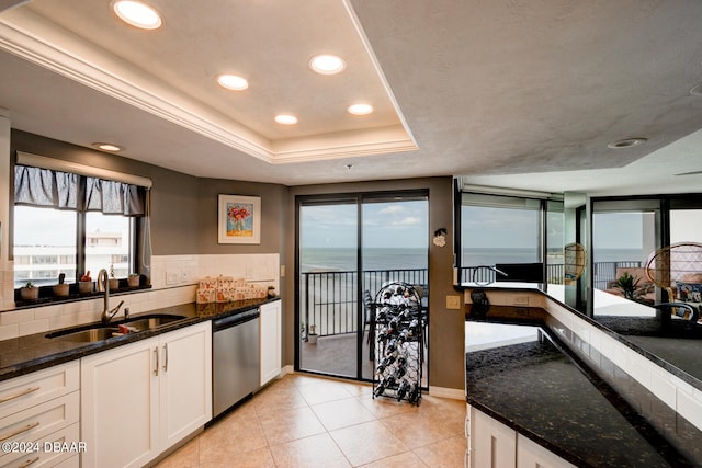 kitchen featuring a wealth of natural light, stainless steel dishwasher, a water view, and sink