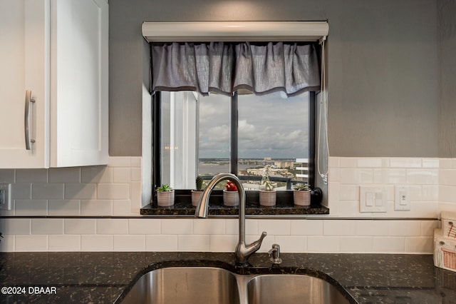 kitchen featuring dark stone countertops, white cabinetry, sink, and tasteful backsplash