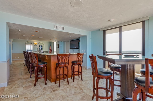 interior space with light stone countertops, a textured ceiling, and a kitchen island