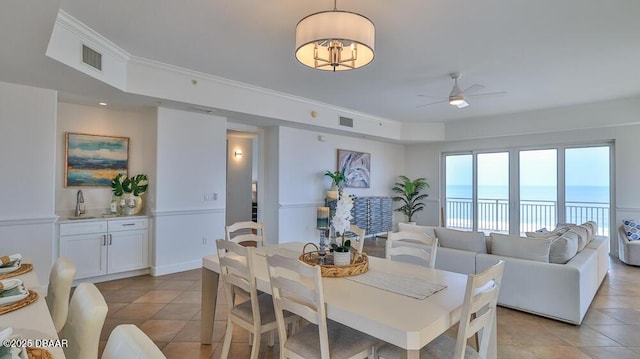 dining area with light tile patterned floors, a ceiling fan, and a water view