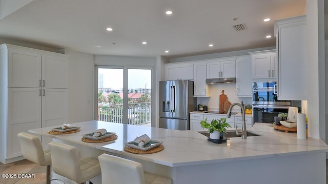 kitchen with appliances with stainless steel finishes, under cabinet range hood, a sink, a peninsula, and white cabinets