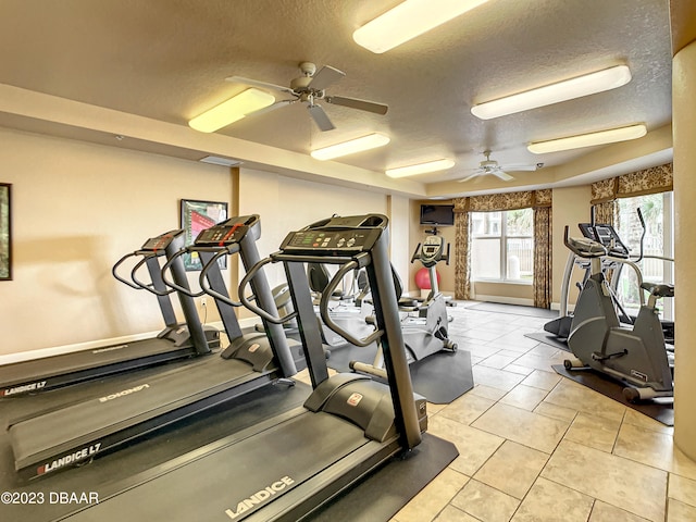 exercise room with ceiling fan, a textured ceiling, and light tile patterned floors