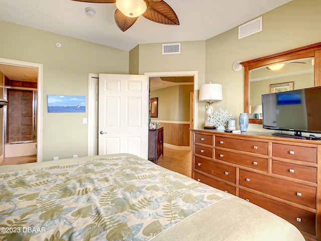 bedroom with ensuite bathroom, wood walls, and ceiling fan