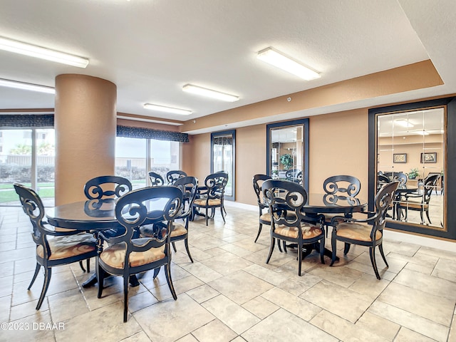 dining area with a textured ceiling, light tile patterned floors, and decorative columns