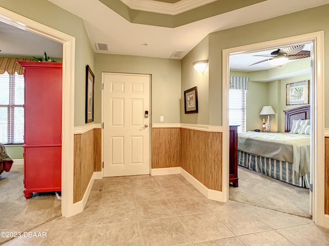 carpeted entryway featuring wood walls, ceiling fan, and crown molding