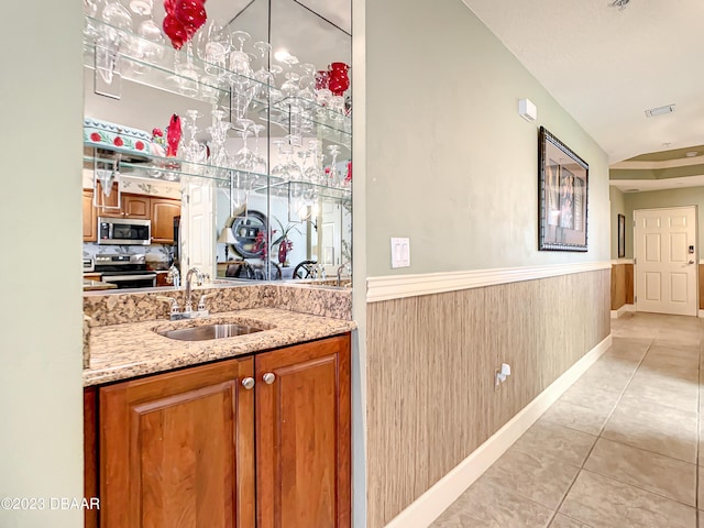 2403 S Atlantic Ave Unit 409, Daytona Beach Shores, FL 32118 - bar with appliances with stainless steel finishes, a sink, light tile patterned floors, and wainscoting